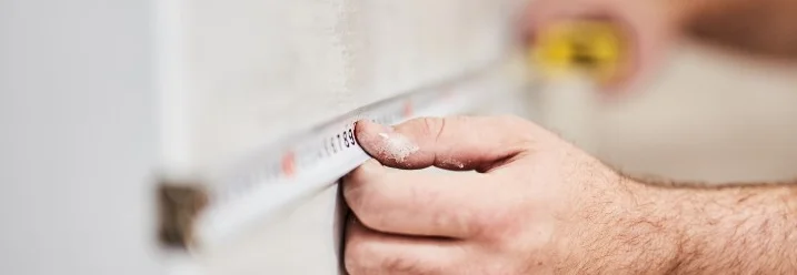 Person misst Wand mit Zollstock aus